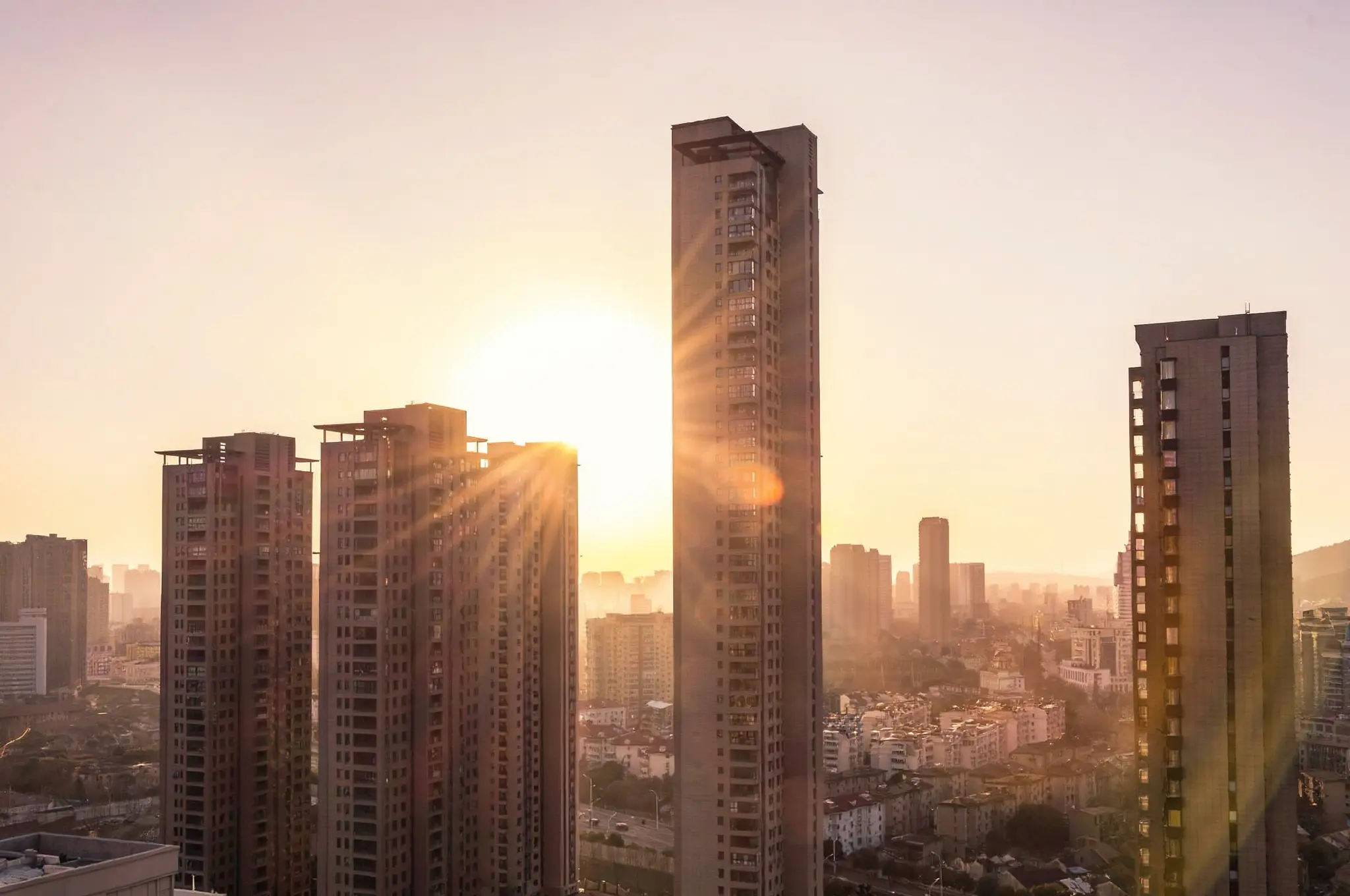 Vista panorâmica de edifícios altos iluminados pela luz dourada do pôr do sol.